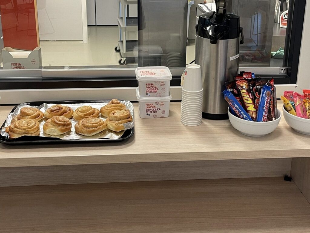 Kafédisken i Kvinnherad Arena med kanelsnurrar, kaffikanne, pappkoppar og sjokolade